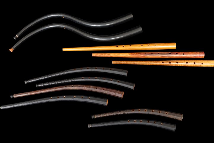 Collection of historic zinks and cornets in various sizes against black background.
