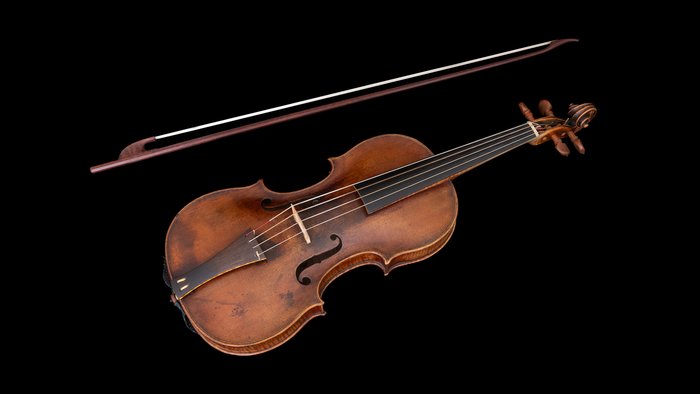 Baroque violin with gut strings and curved body on black background.