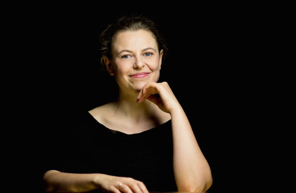 Porträt von Johanna Bookmeyer mit Kinn auf der Hand vor schwarzem Hintergrund.