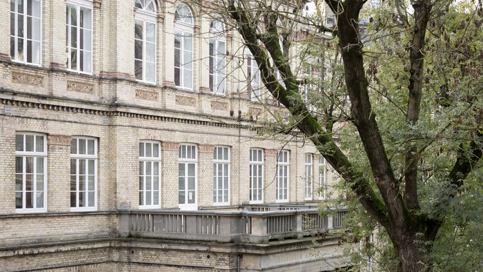 Historisches Backsteingebäude in der Dechanatstraße, das den Fachbereich Musik der HfK Bremen beherbergt, teilweise von Bäumen verdeckt.