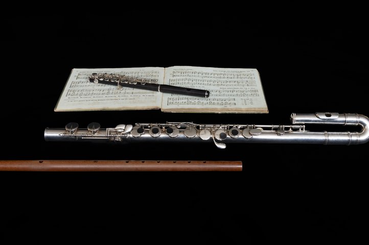 Collection of historic flutes beside open music score book.