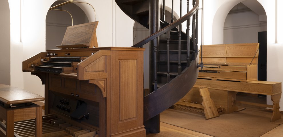 Interior view of the music department at HfK Bremen, featuring wooden organs and a spiral staircase on Dechanatstraße.