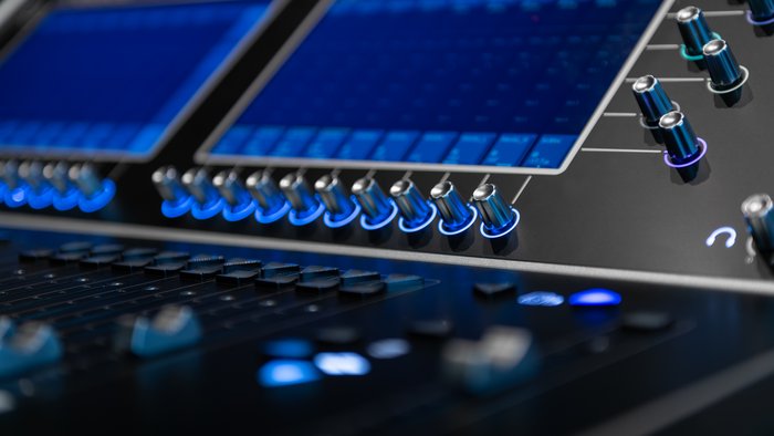 Blue-lit digital mixing console with faders and display.