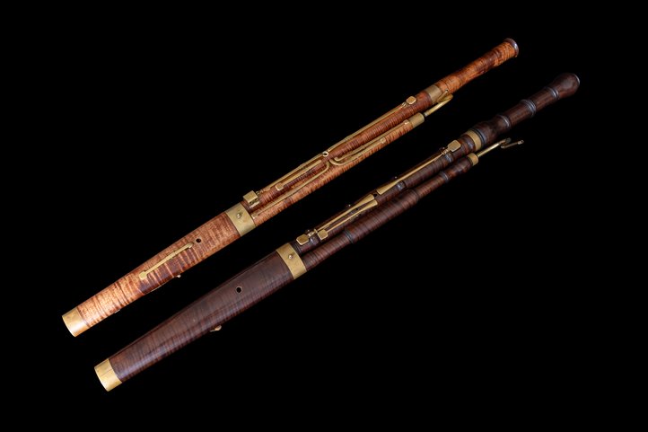 Baroque bassoon of light maple wood with brass keys on black background.