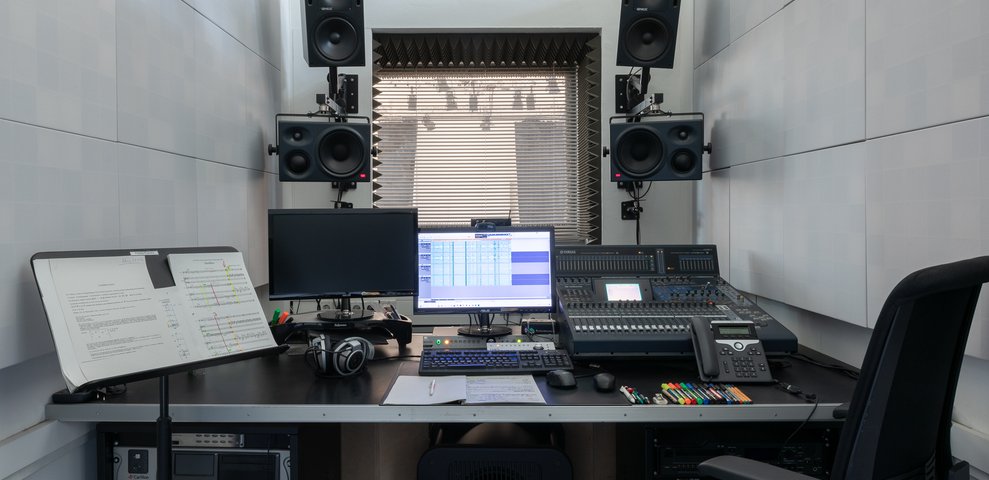 Recording Studio at HfK Bremen featuring mixing console, dual monitors, headphones, and wall-mounted speakers.