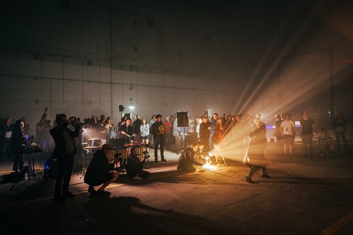 Eine Performance im Bunker Valentin mit Musikern und Publikum, beleuchtet von dramatischem Licht.