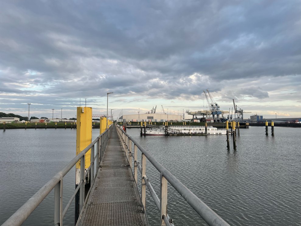 Metallsteg zum Anleger am Lankenauer Höft, MS Dauerwelle im Industriehafen bei bewölktem Himmel.