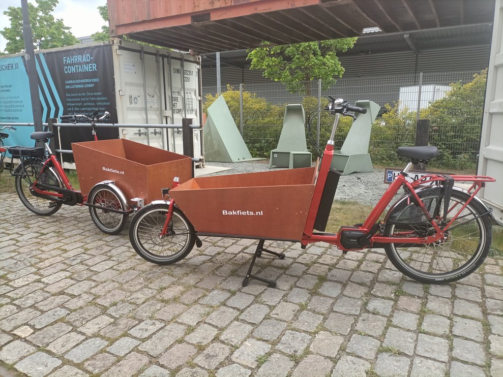Zwei rote Lastenräder vor dem Fahrrad-Container mit Schild am Speicher XI.