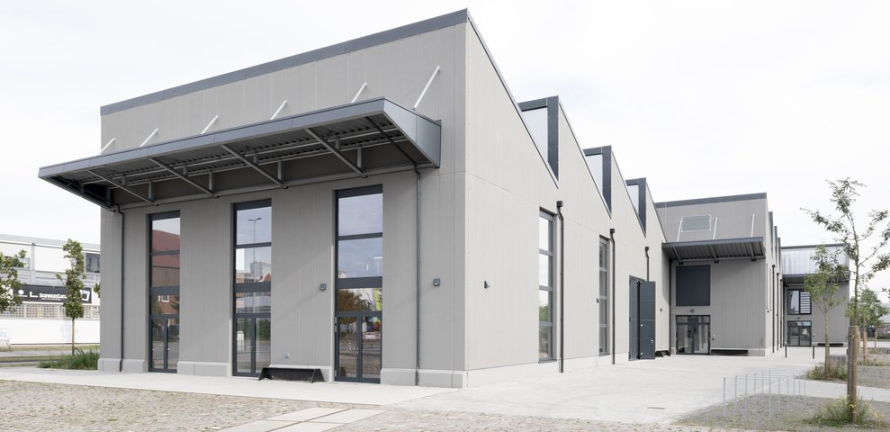 Speicher XI A an der Hochschule für Künste Bremen präsentiert modernes architektonisches Design mit großen Fenstern und einer minimalistischen Fassade, gelegen in einem Kopfsteinpflasterhof.