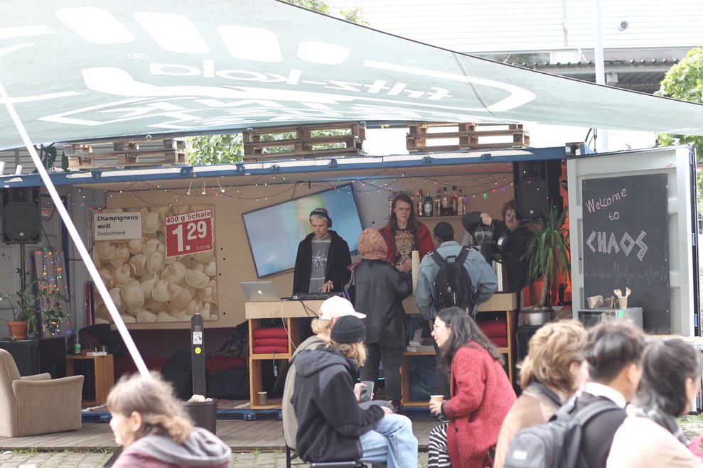 AStA-Bar im umgebauten Container mit DJ-Pult, Lichterkette und Schriftzug Chaos.