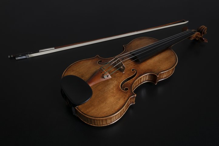 Violin with warm wooden tone against black background.