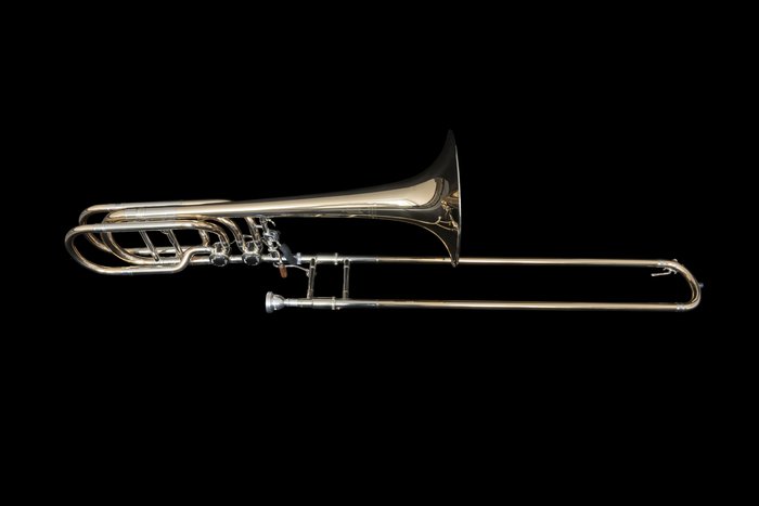 Bass trombone with large bell and valve on black background.