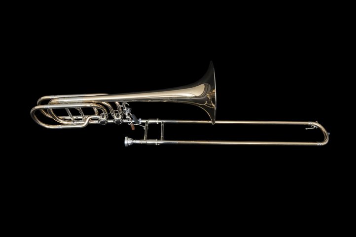 Bassposaune mit großem Schallbecher und Quartventil vor schwarzem Hintergrund.