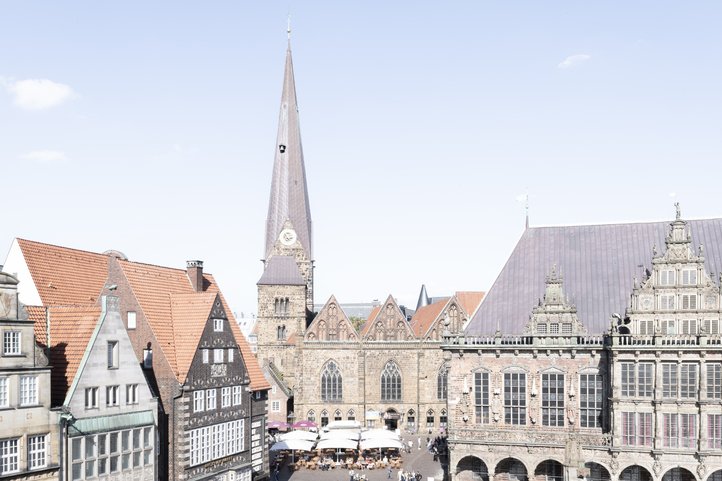 Vogelperspektive des Bremer Marktplatzes, mit historischen Gebäuden und dem hohen Turm der Unser Lieben Frauen Kirche unter klarem Himmel