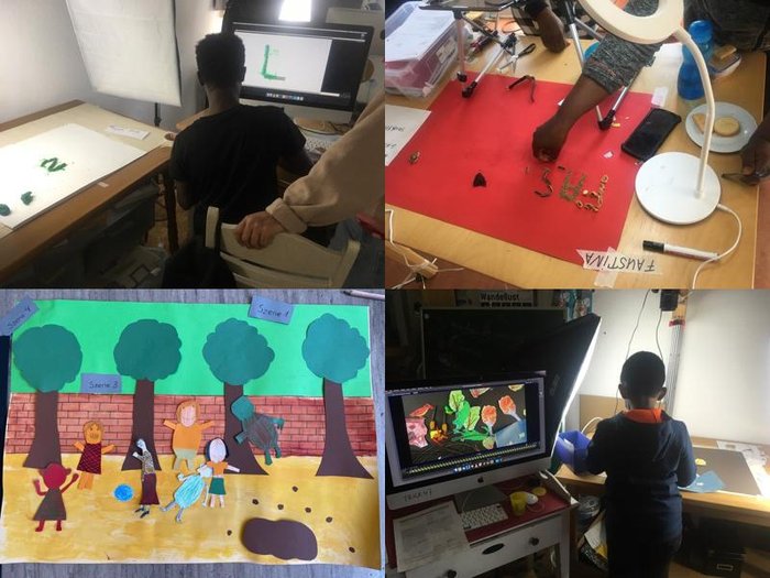 People, among them children, are working on a stop-motion animation project. They create characters and backgrounds from paper and other materials, take photos with cameras, and animate scenes on computers.