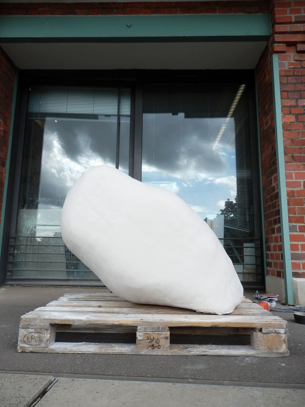 Große weiße organische Skulptur auf Holzpalette in der Ausstellung von Sabine Peter.