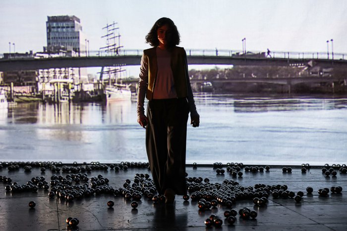 Schauspielerin Emma Floßmann vor einem Weserblick des Videografen Patrick Peljhan, links hinten das Hochaus des "Kühne + Nagel"-Konzerns.