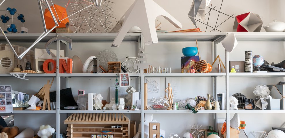 Regalwand mit dreidimensionalen Entwurfsmodellen und Prototypen aus verschiedenen Materialien.