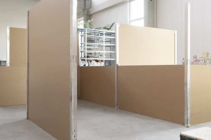Interior view of Speicher XI A at HfK Bremen, featuring partition walls and industrial design elements such as exposed pipes and large windows.