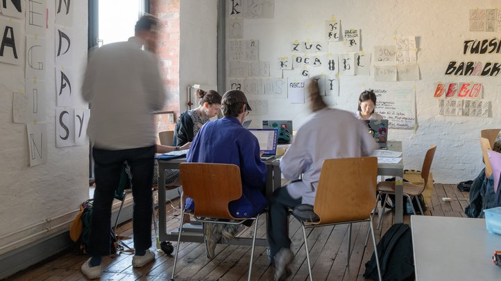 Studierende arbeiten im Typografie-Projektraum mit Schriftentwürfen an den Wänden.