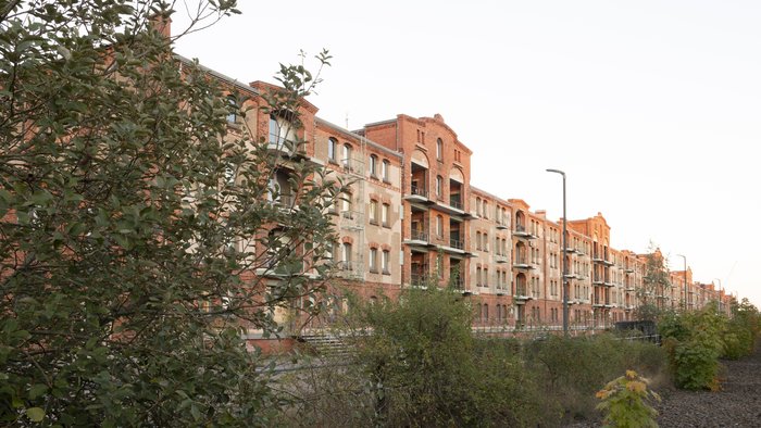 Historic brick warehouse Speicher XI, exterior view at HfK Bremen, with lush greenery in the foreground.