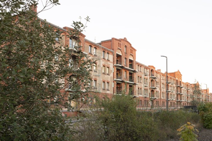Historic brick warehouse Speicher XI, exterior view at HfK Bremen, with lush greenery in the foreground.